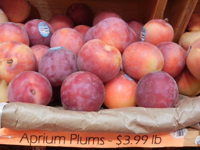 Aprium plums on a shelf with a sign reading: Aprium Plums - $3.99 lb
