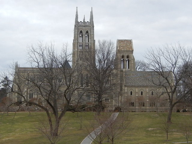 A stone cathedral in winter, surrounded by large greenish-tan lawns and bare trees