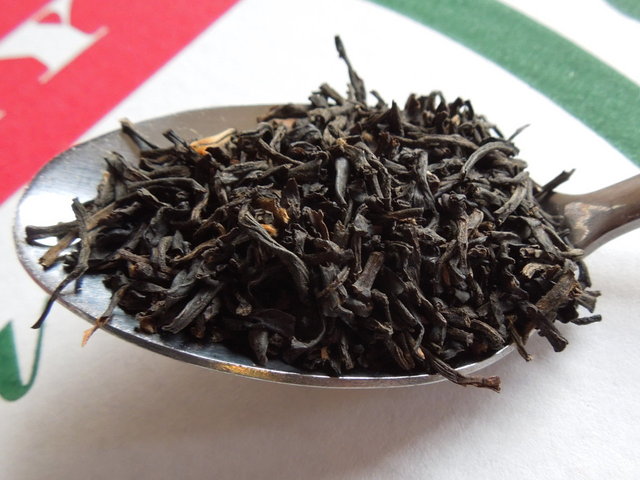 A spoon of loose-leaf black tea, showing large, dark intact leaves