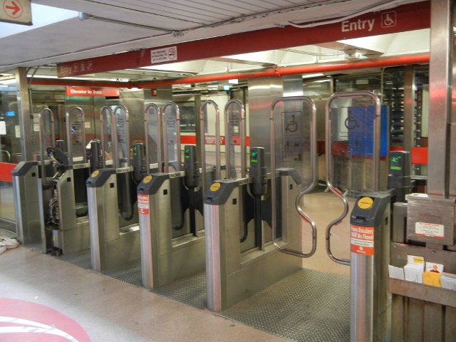 Entry gates at a transit station, with red trim reading Entry, one gate wider with a handicap-accessible sign on it