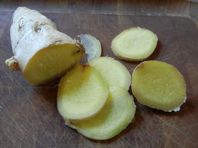 A ginger root and thin slices, on a cutting board