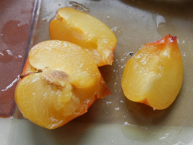 A golden tree pluot, sliced, a plum-like fruit with yellow flesh, on a ceramic plate