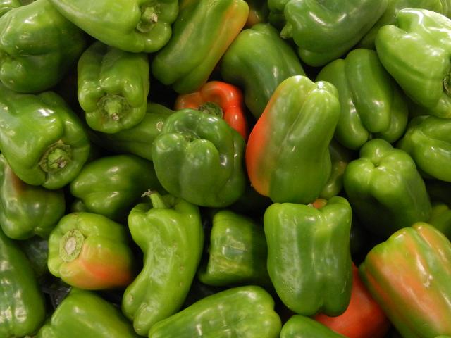 Many large green bell peppers with some red color on some