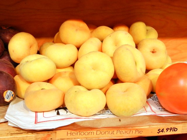 All yellow donut peaches on a shelf, with a sign reading Heirloom Donut Peach Pie, $4.99lb