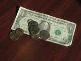 A dollar bill on a table, with four quarters on it, and one penny