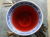 A small chinese teacup, on a hotplate, filled with a deep red liquid
