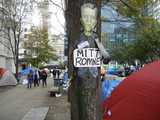 A picture of Frankenstein, labelled Mitt Romney, attached to a tree, surrounded by tents in a city