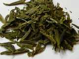 Flat green tea leaves, with a rich golden-yellowish green color