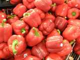 Large red bell peppers with green stems and produce stickers
