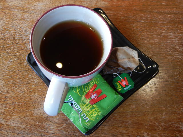 Mug of black tea, with Wissotzky Tea Classic tea bag and wrapper on plate next to mug