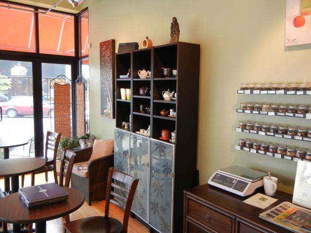 The wall in a tea shop, with small jars of tea, and shelves with teaware, and a scale