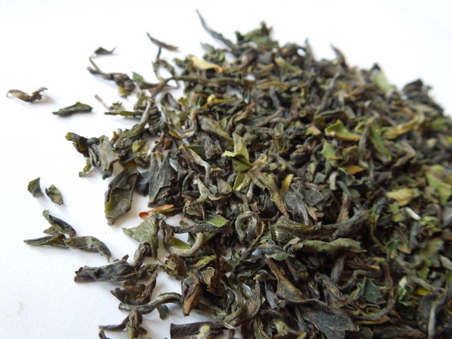 Fine tea leaves with a heterogenerous color, ranging from light green to brown, curly, some with fine hairs