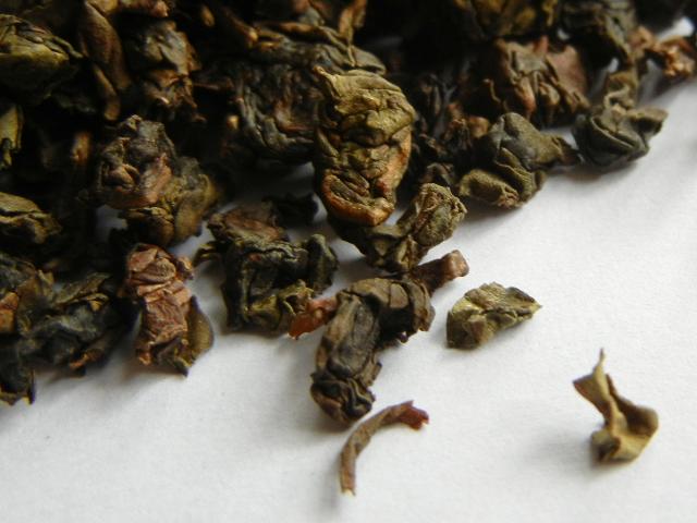 Tightly rolled loose-leaf oolong tea, showing an olive color
