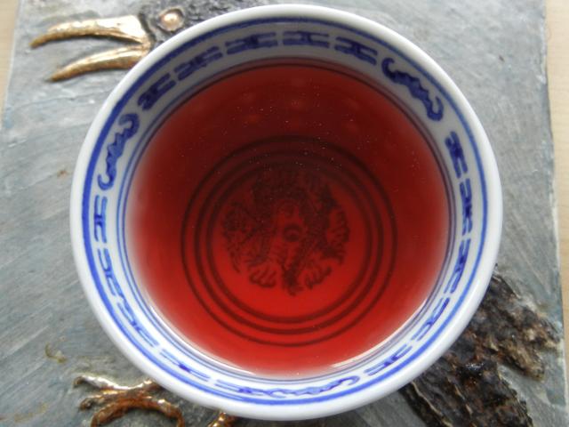 A small chinese teacup, on a hotplate, filled with a deep red liquid