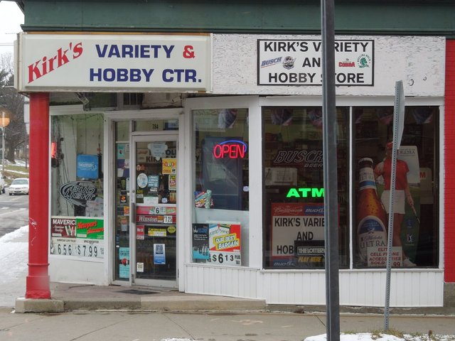 A store reading Kirk's Variety & Hobby Ctr. and showing ads for cigarettes and beer