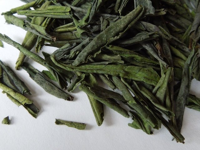 Loose-leaf green tea showing large, curled leaves with a vibrant green color