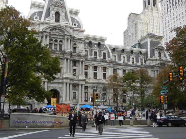 Philadelphia's city hall viewed from a distance, with protesters and tents in front