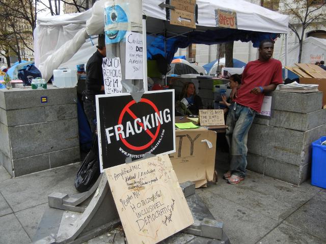 A tent at a protest, with a small sign: SAFETY, among other signs, including a bold sign against fracking
