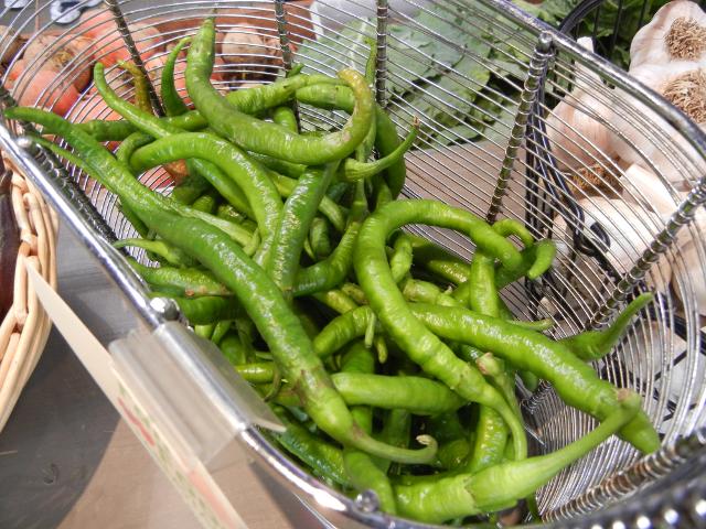 Organic cayenne peppers, long, narrow, green, slightly crinkly peppers, in a metal basket