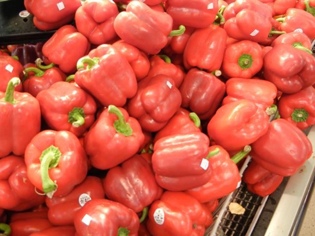 Large red bell peppers with green stems and produce stickers