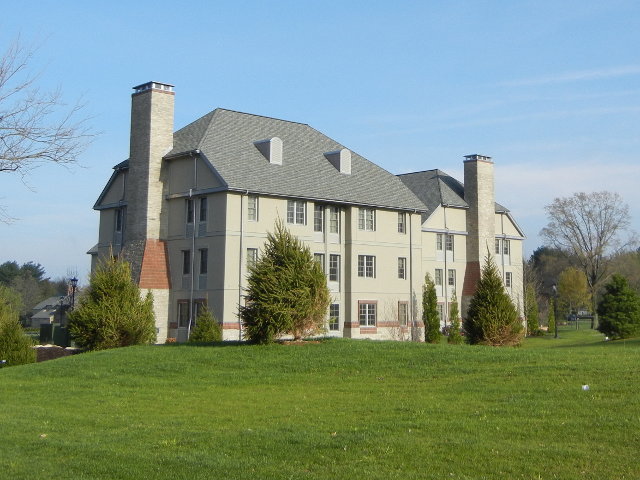 A brand-new gray building with gray roof, built an older style, surrounded by sterile, empty green lawn