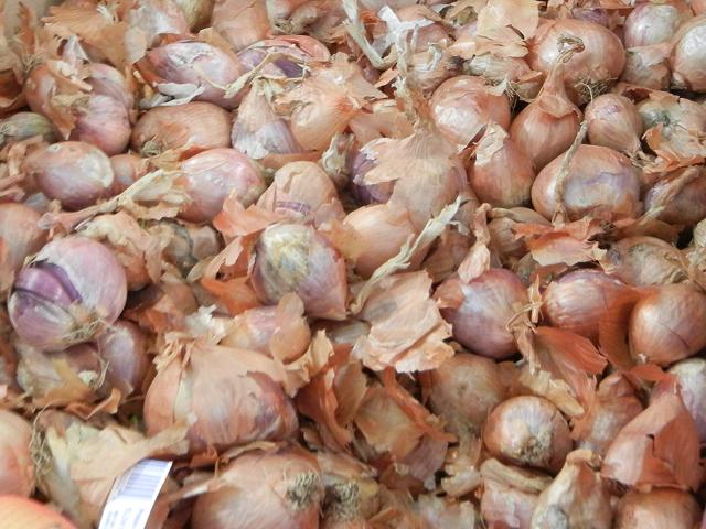 A bin of shallots, small onions with a reddish interior and yellowish outer skin