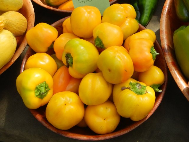 A basket of round, yellow peppers, bell-pepper shaped but rounder, with green stems