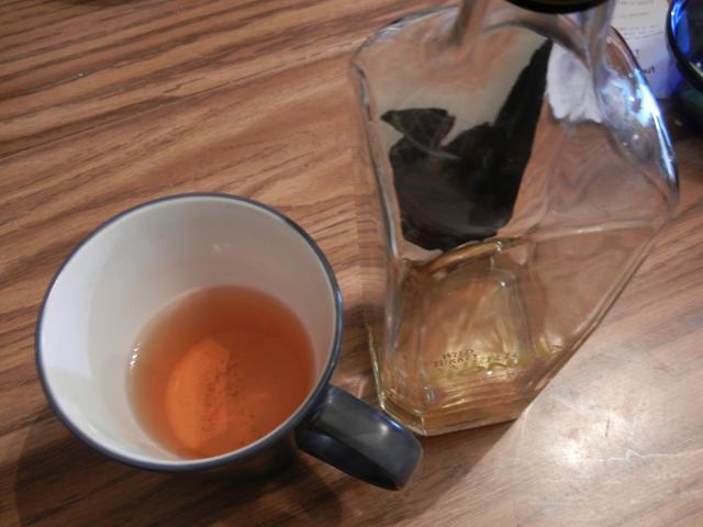 A mostly empty mug of tea, next to a bottle of Wild Turkey American Honey bourbon