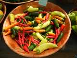 Assorted hot peppers in a bowl,showing long, narrow red peppers, small, shiny green, pale yellow-green, and small carrot-colored ones