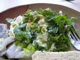 A plate with a mix of cottage cheese, diced green hot peppers, and fresh mint leaves, with some bread and pickled herring around the edge