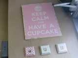 A pink sign with white lettering reading: Keep Calm and Have a Cupcake, with three little cupcake pictures beneath