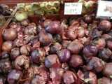 A bin of red onions, with a sign reading: red onion, 79 cents -lb-