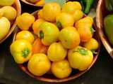 A basket of round, yellow peppers, bell-pepper shaped but rounder, with green stems