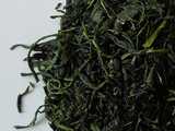 Close-up of loose leaf tamaryokucha tea, with thin, small twisted green leaves of an intense green color