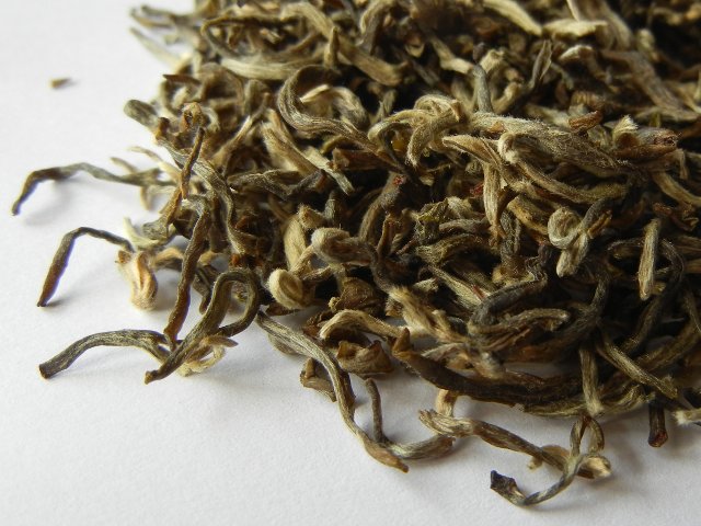 Loose-leaf tea with a yellowish color, slightly twisted leaf tips covered in downy hair